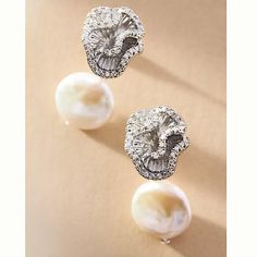 two pearl and diamond earrings on a beige background