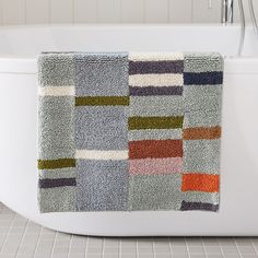 a bath tub with a multicolored towel hanging on it's side in a bathroom