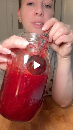 a woman holding a jar filled with liquid