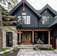 a large black house with two story windows and stone walkway leading to the front door