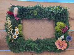 an arrangement of flowers and plants arranged in a rectangle on a wooden table top