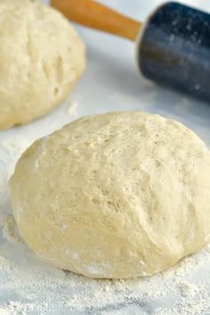 two uncooked doughnuts sitting on top of flour next to a rolling pin