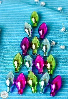 many different colored lights on a blue cloth with silver pins and other items around them