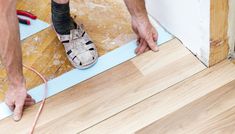 a man is working on the floor with a tape and a pair of shoes in front of him