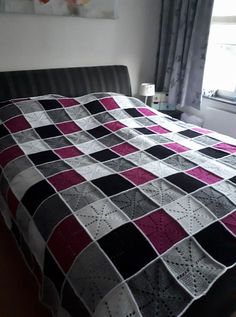 a bed with a quilt on top of it in a bedroom next to a window