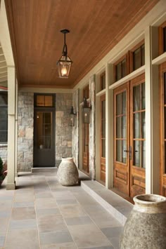 an image of a porch with stone pillars and doors on the side walk, along with a lantern light