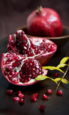 two pomegranates on a table with leaves