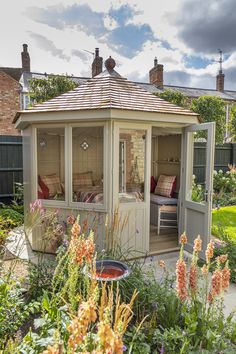 a gazebo in the middle of a garden with flowers and plants around it,