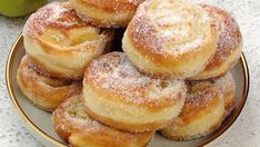 powdered sugar covered donuts on a plate next to an apple