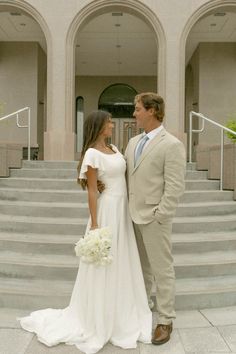 a bride and groom standing in front of some stairs