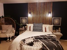 a bedroom with black walls, white bedding and wicker furniture in the corner