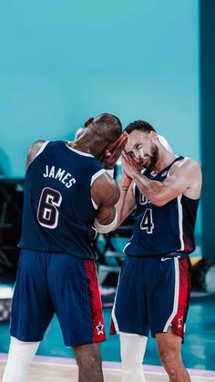 two basketball players standing next to each other with their hands in their pockets and one is covering his face