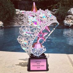 a crystal trophy with a pink star on top next to a pool in the background