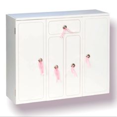 a white cabinet with pink handles and knobs on the doors is against a white background