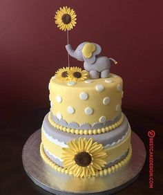 a yellow and gray cake with sunflowers on the top is sitting on a table