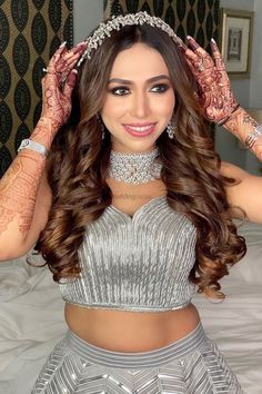 a woman in a silver dress with henna on her head and hands behind her head