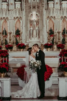 a bride and groom standing in front of a church altar with red flowers on it