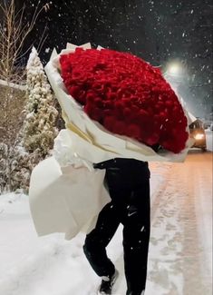 a man is walking in the snow holding a bouquet of roses