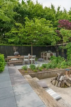 an outdoor patio with fire pit, table and chairs in the back yard surrounded by trees