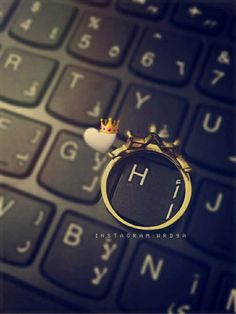 a gold ring sitting on top of a computer keyboard with the letter h in front of it