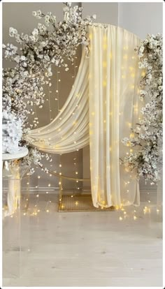 a white wedding arch decorated with flowers and fairy lights