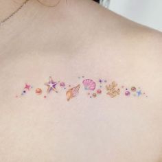 the back of a woman's shoulder with tattoos on her chest and seashells