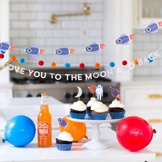 cupcakes and drinks on a table in a kitchen decorated for an astronaut themed birthday party