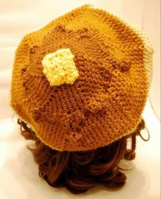 a knitted hat with a yellow flower on the top is shown in close up