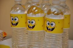 three plastic water bottles with cartoon faces on them sitting on a table next to plates