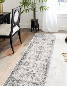 a white and black rug in a living room with a chair, potted plant and window