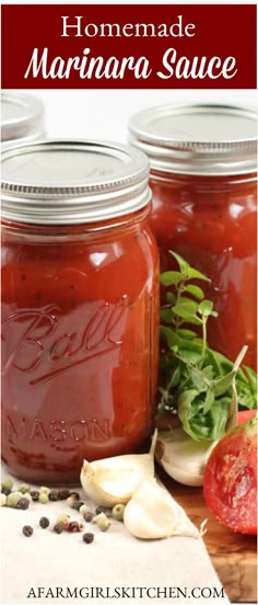 homemade marinara sauce in mason jars on a cutting board with tomatoes and garlic next to it