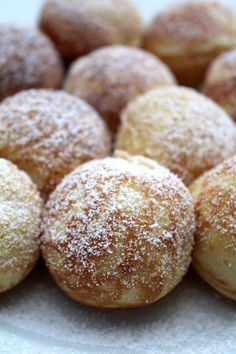 powdered sugar covered donuts sitting on top of a white plate