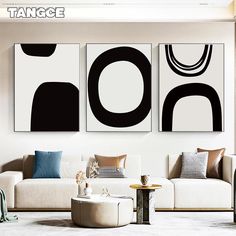 three black and white paintings hanging in a living room