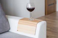 a glass of wine sitting on top of a white couch next to a wooden table