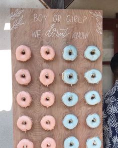 a man standing in front of a sign with donuts on it that say boy or girl we don't know