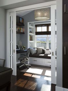 an open door leading to a living room with a window seat and bookshelf