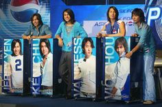 four people standing behind signs with pepsi advertising on them