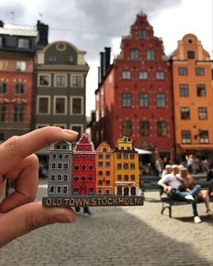 a person holding up a small sticker with buildings on it in the middle of a city