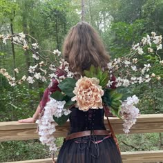 a woman in a dress with flowers on her back, looking over a wooden fence