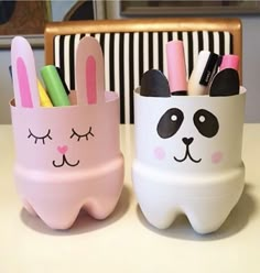 two white and pink pencil holders with faces painted on them, one is shaped like a bunny and the other has a panda face