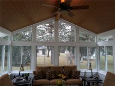 a living room filled with furniture and windows covered in wood planks on the ceiling