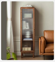 a brown leather chair sitting next to a tall wooden cabinet with books on it's sides