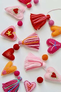 several different types of felt hearts on a white surface with pom - poms