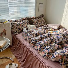 an unmade bed in a bedroom with pink sheets and flowers on the comforter