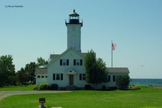 a white house with a light tower in the middle of it's front yard