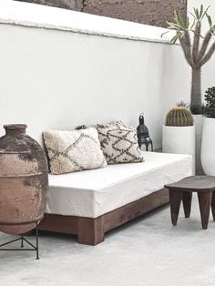 a white couch sitting on top of a floor next to potted plants