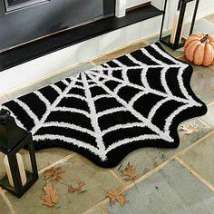 a black and white spider web rug next to a lantern