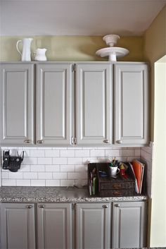 a kitchen with white cabinets and granite counter tops in front of an overhead light fixture