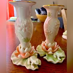 two white vases sitting on top of a wooden table next to eachother