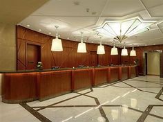 an empty reception room with lights and wood paneling on the walls, along with marble flooring